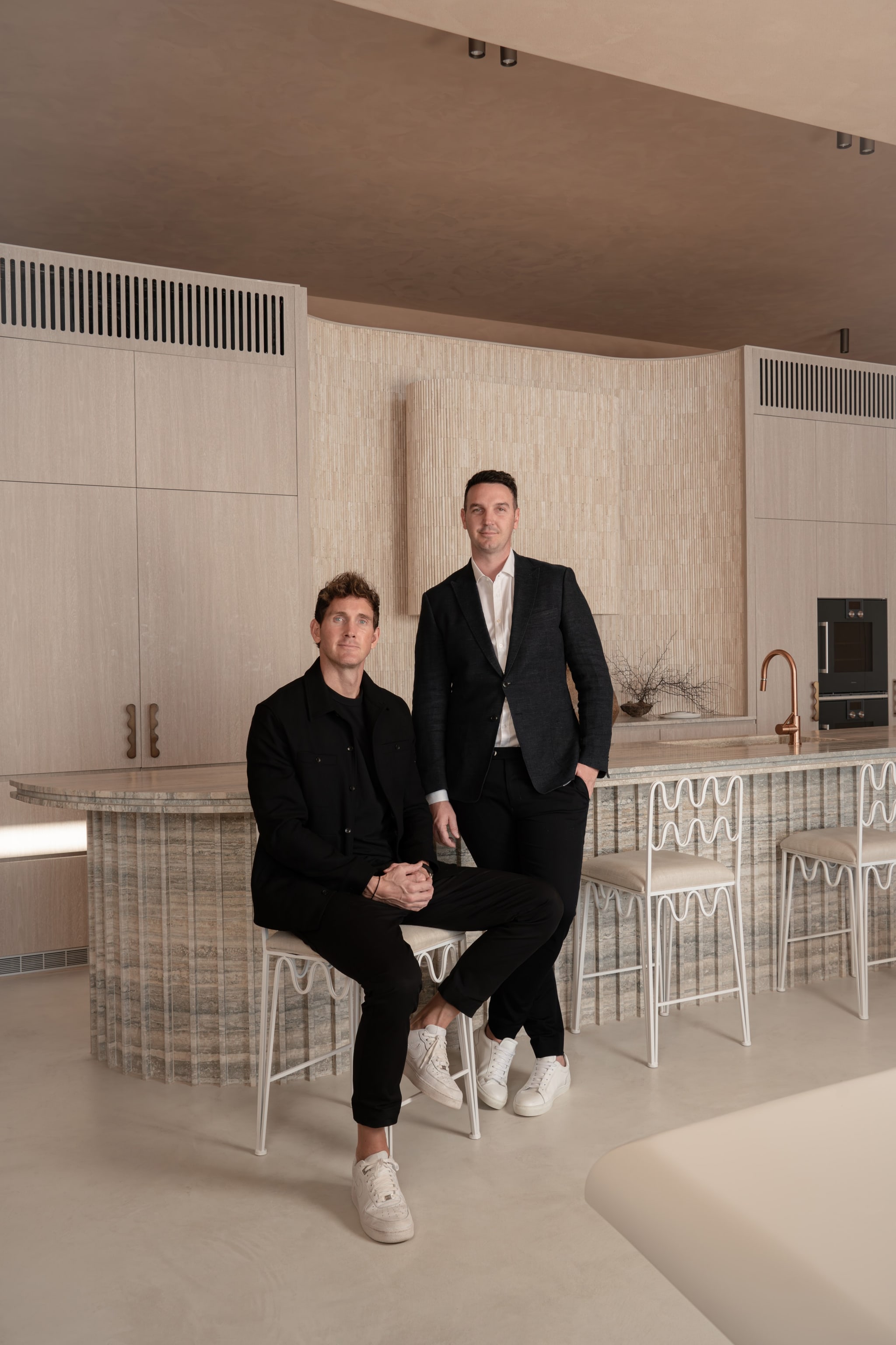 Two founders at a travertine kitchen island. Graya