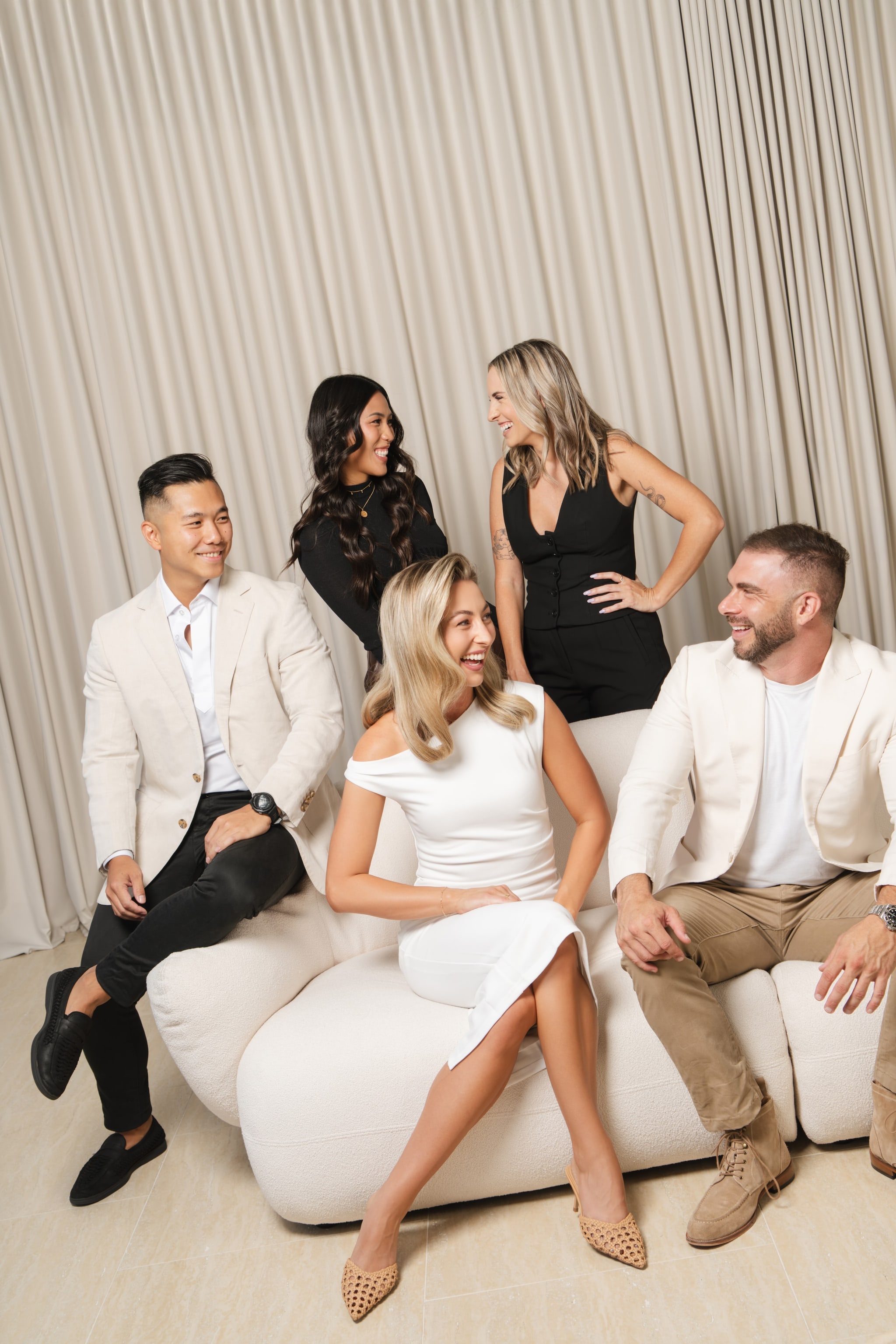 Group of five against a pleated curtain backdrop on a cream curved sofa. Space Property